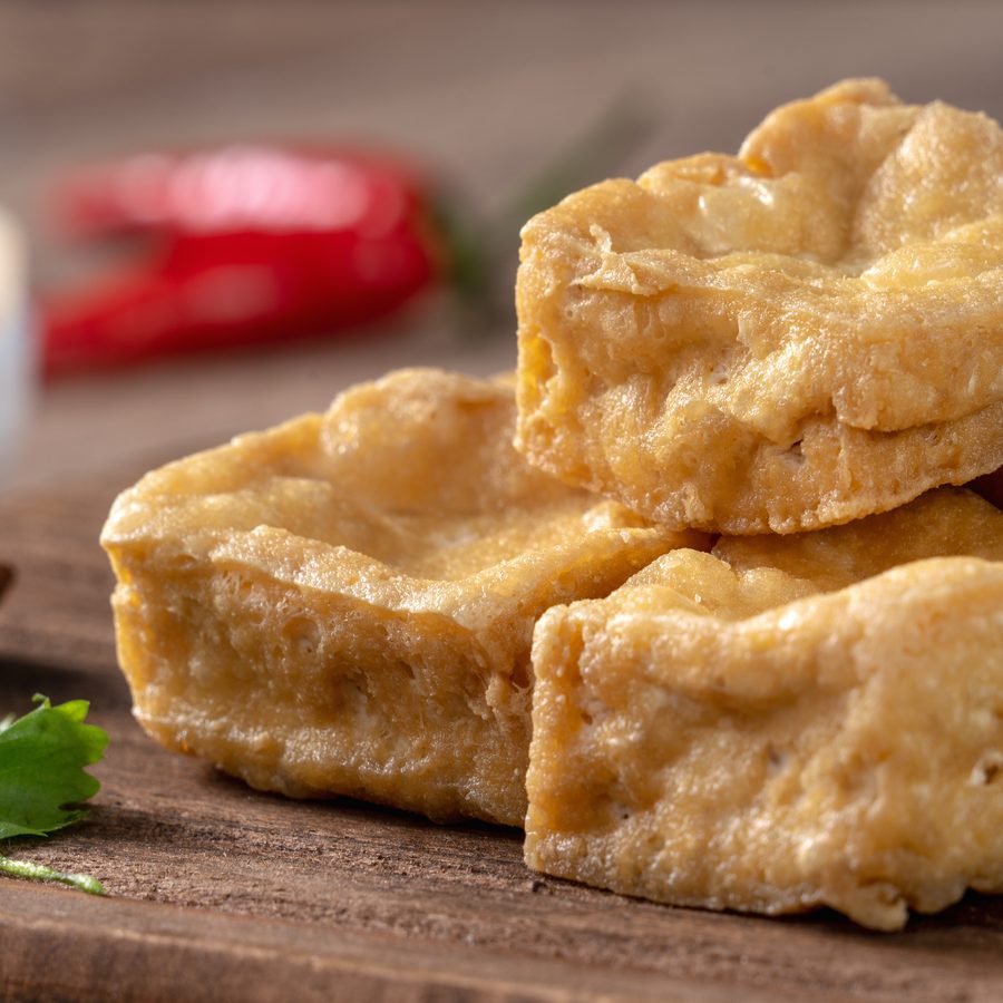 Deep fried stinky tofu served on a wooden board with fresh chilli and coriander