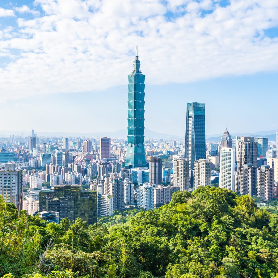 Taipei 101 rising above the city skyline, seen over green hillside in daylight