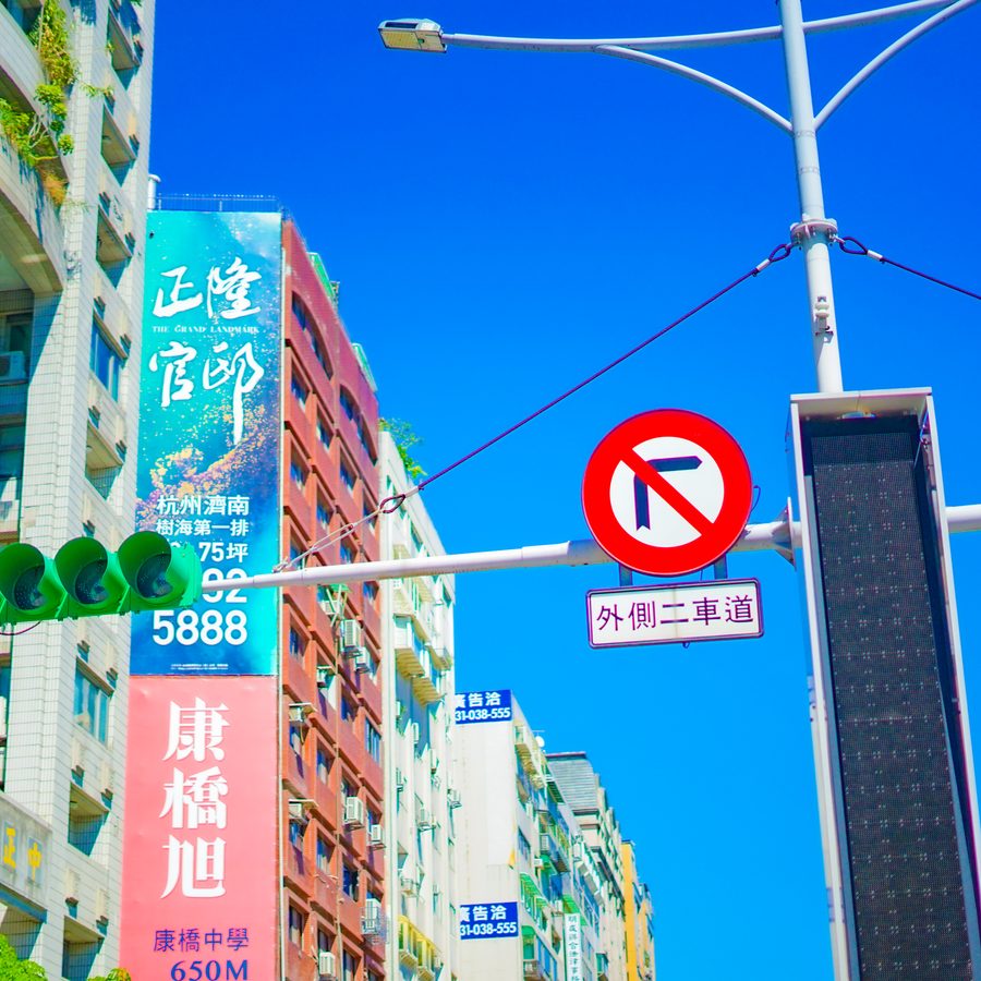 Colourful Taiwanese shop banners, traffic lights and road signs against a blue sky in Taipei